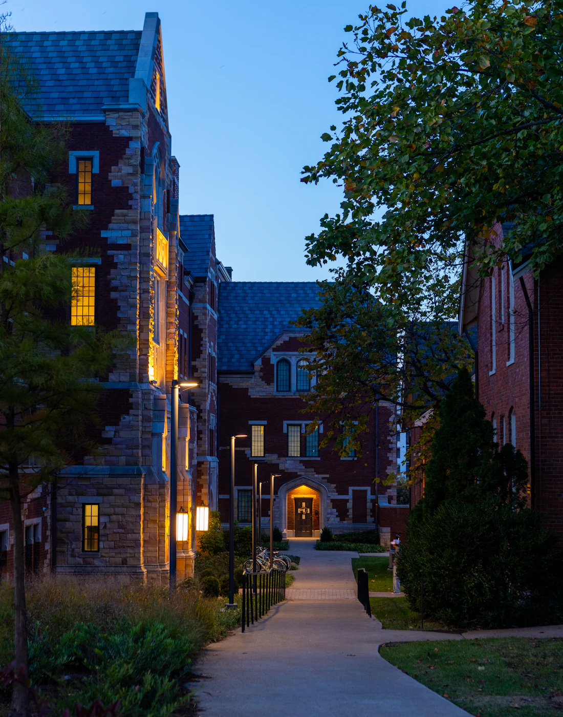 A lit path between buildings leading to a door at dusk